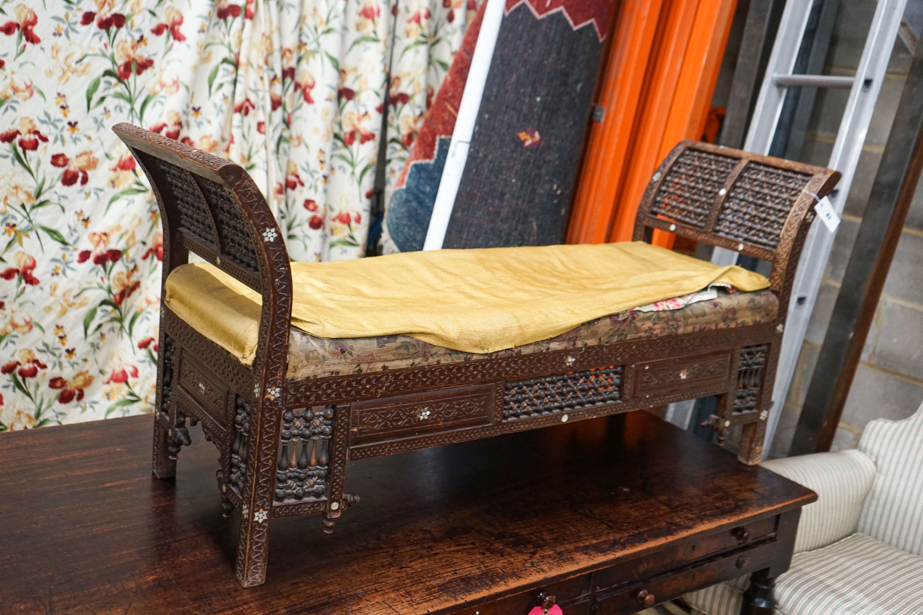 An early 20th century Moorish mother of pearl inlaid carved hardwood window seat, length 134cm, depth 44cm, height 64cm